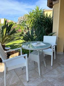 einen Glastisch und zwei Stühle auf einer Terrasse in der Unterkunft Hotel Sa Suergia in Villasimius