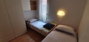 Duas camas num pequeno quarto com uma janela em Lorena app em Umag