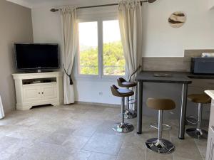 a kitchen with a table and stools and a television at Agréable appartement vue mer in Les Issambres