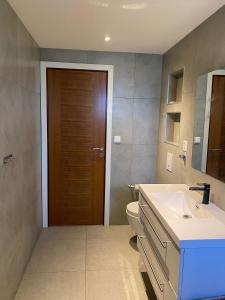 baño con lavabo, aseo y puerta en Moderne Leilighet med panorama utsikt, en Sandefjord