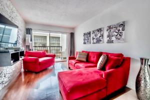 1 sofá rojo y 2 sillas en la sala de estar. en Amazing condo 5 minute walk to the beach!, en Miami Beach