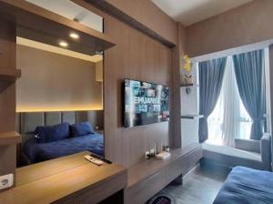 um quarto com uma cama, uma televisão e uma janela em The Alton Apartemen Type Studio em Jatingaleh