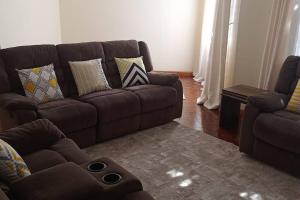 - un salon avec un canapé brun et une chaise dans l'établissement Stylish, Exquisite apartment in Nairobi, à Nairobi