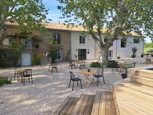 a patio with tables and chairs in front of a building at Hôtel Le Cottage de Sophie in Valernes