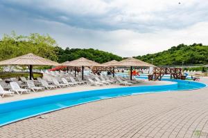 a pool at a resort with chairs and umbrellas at Casutele Deny Băile Figa cu aer condiționat in Beclean
