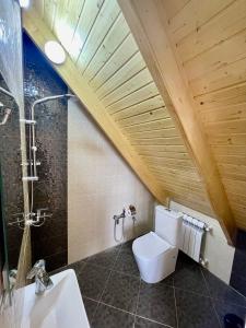 a bathroom with a white toilet and a wooden ceiling at EMIREST Barnhouse in Gabala