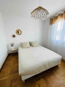 a white bedroom with a bed and a chandelier at Appartement bohème in Manosque