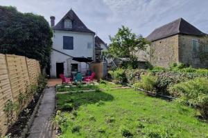 un patio con sillas rojas y una casa blanca en Appartement dans Maison de ville - 4 personnes, en Oloron-Sainte-Marie