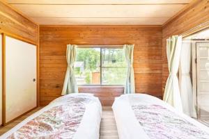 two beds in a room with a window at 那須ウッドペッカーBBQ & Petりんどう湖近くの一棟貸別荘 in Nasu