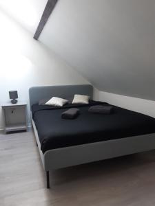 sypialnia z czarnym łóżkiem na poddaszu w obiekcie charmant logement d'Amiens w Amiens