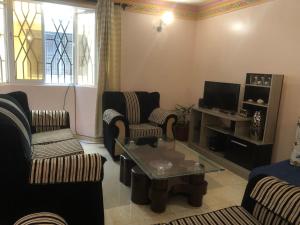 a living room with two chairs and a tv at Asali Nyali 2Br Peaceful Serviced Apartment Beach and Dining nearby in Mombasa