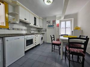 een keuken met witte kasten en een tafel en stoelen bij 13A02 Céntrico 4 dormitorios in Ribadesella