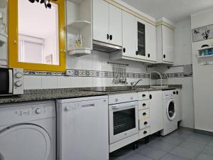 een keuken met witte kasten en een wasmachine en droger bij 13A02 Céntrico 4 dormitorios in Ribadesella