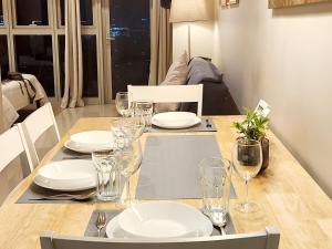 a dining room table with plates and glasses on it at Casa Antonio At Uptown Parksuites Two in Manila