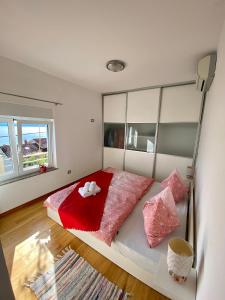 a bedroom with a large bed with red sheets and pink pillows at Apartments Belvedere Lovran in Lovran