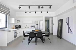 a white kitchen with a black table and black chairs at Ambassador apartment+parking in Tel Aviv