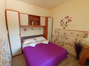 a bedroom with a purple bed in a room at Apartment Igralište Mirakul in Seget Vranjica