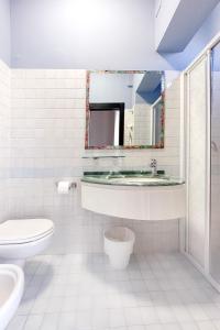 uma casa de banho com um lavatório, um WC e um espelho. em Lime Hotel em Rimini