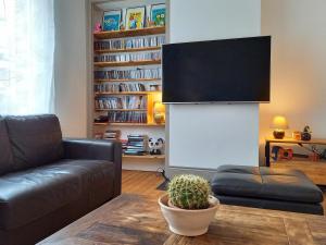 een woonkamer met een bank en een flatscreen-tv bij Maison familiale de charme au coeur de Rosendael in Duinkerke