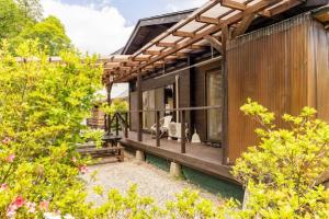 una casa de madera con porche y algunos arbustos en ウッドペッカー小径 en Nasu