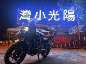 Una motocicleta negra estacionada frente a un cartel en 陽光小灣旅店 en Kenting
