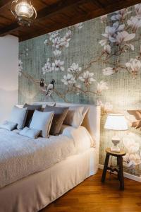 1 dormitorio con 1 cama grande y pared de flores en Historical Penthouse on Isola dei Pescatori, en Someraro