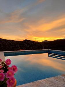 a swimming pool with a sunset in the background at Apartment Igralište Mirakul in Seget Vranjica