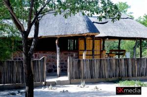 Cabaña de madera con techo de paja y valla en Mokoka Rest Camp, en Nata