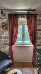 a living room with a window with red curtains at Casa Vita Nova in Perast