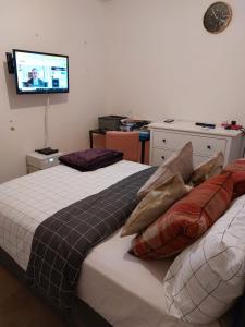 a bedroom with a bed with pillows and a tv on the wall at Nice and comfortable Shared Flat in Surbiton in Malden
