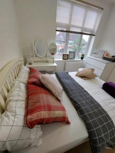 um quarto com uma cama com almofadas e uma janela em Nice and comfortable Shared Flat in Surbiton em Malden