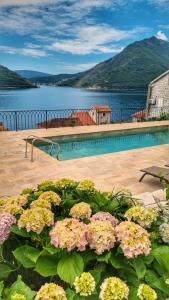 a swimming pool with flowers in front of a body of water at Casa Vita Nova in Perast