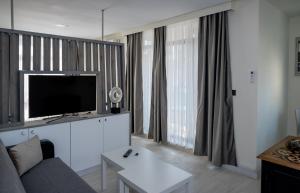 uma sala de estar com um sofá e uma televisão de ecrã plano em ADIRAMAR Apartments em Obzor