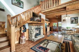 a living room with a stone fireplace and wooden stairs at 2 Miles from Dollywood Family Resort with Seasonal Outdoor Swimming Pool, Year around Heated Indoor Swimming Pool, Townhome Style Cabin, Private Hot Tub, Arcade, TV, Wifi, Kitchen with Refrigerator, Washer and Dryer in Pigeon Forge