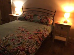 a bed with a floral bedspread and two tables with lamps at Mary's in Selby