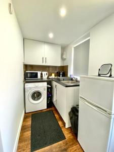 uma cozinha com armários brancos e uma máquina de lavar e secar roupa em Kyle house em Longley