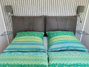 ein Bett mit zwei Kissen darauf und zwei Tischen in der Unterkunft AnNa Home & Sunny Home Apartments in Karlsruhe
