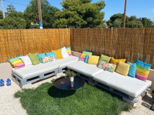 a white couch with colorful pillows sitting on the grass at Philia Apartment in Artemida