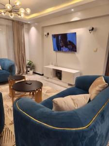 uma sala de estar com um sofá azul e uma televisão em C&C Apartment at Kileleshwa em Nairobi