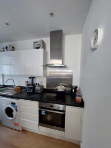 uma cozinha com armários brancos e um forno com placa de fogão em Nice and comfortable Shared Flat in Surbiton em Malden