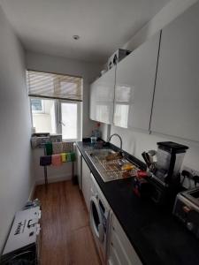 uma cozinha com armários brancos e um balcão preto em Nice and comfortable Shared Flat in Surbiton em Malden