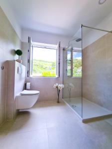 een badkamer met een douche, een toilet en een raam bij Apartment Gulić in Rab