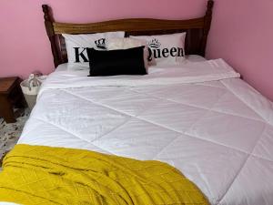 ein weißes Bett mit einer schwarzen und gelben Decke in der Unterkunft Ruth's Studio - Kericho in Kericho