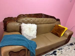 a brown leather couch with two pillows on it at Ruth's Studio - Kericho in Kericho