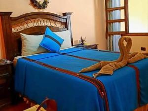 un peluche è seduto su un letto blu di Hotel Casa Sofia a Antigua Guatemala