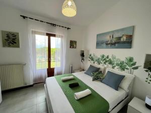 1 dormitorio con 1 cama blanca grande con detalles verdes en Confortevole appartamento nella natura FREE PARKING, en Castel di Leva