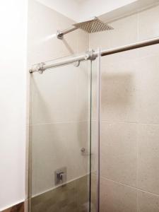 La salle de bains est pourvue d'une douche avec une porte en verre. dans l'établissement Aw Hotel Pasarela Real, à Cali