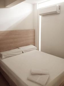 Aw Hotel Pasarela Real في كالي: سرير ابيض مع وسادتين ونافذة
