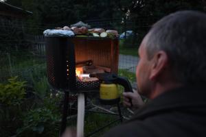 a woman is cooking food in a grill at Bieszczady Smolnik Cottage 2 in Smolnik