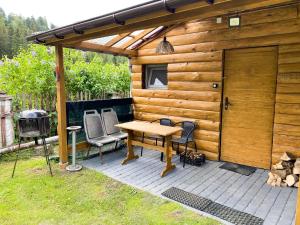 a wooden cabin with a table and chairs and a grill at Bieszczady Smolnik Cottage 2 in Smolnik